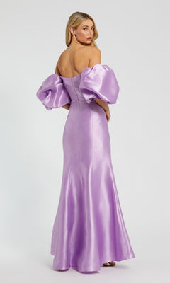 A woman stands looking over her shoulder in the Mac Duggal 50677 Off-the-Shoulder Long Gala Gown, a shiny lavender formal dress with voluminous puff sleeves.