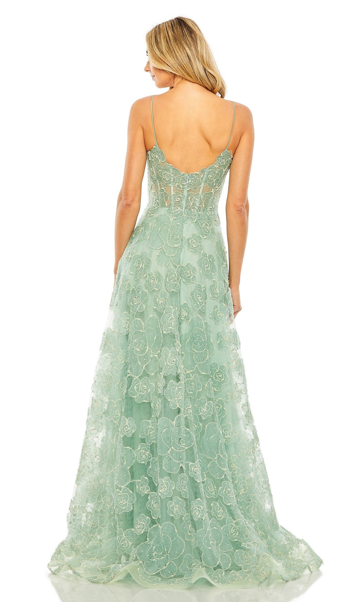 A woman stands facing away from the camera, wearing the Mac Duggal 50735 long formal dress in light green with thin straps and a semi-sheer back.