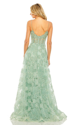 A woman stands facing away from the camera, wearing the Mac Duggal 50735 long formal dress in light green with thin straps and a semi-sheer back.
