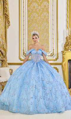 A woman in the Quinceanera Dress 5076 by Dancing Queen in Bahama Blue and a tiara stands in an ornate gold and white room with decorative curtains and a fireplace.