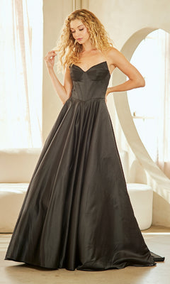 Woman wearing a black a-line evening gown with a corset bodice in a bright room with large windows.
