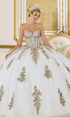 A woman in the Quinceanera Dress 5085 By Dancing Queen, featuring an ivory strapless sweetheart corset with gold sequin applique, stands in an ornate gold-accented room, crowned with a jeweled tiara.