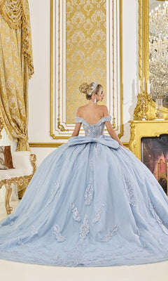 A woman in the Dusty Blue Quinceanera Dress 5089 by Dancing Queen, featuring off-the-shoulder lace applique, stands with her back to the camera in an ornate gold-decorated room.