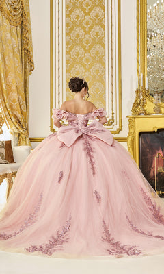 A woman in the Quinceanera Dress 5106 By Dancing Queen, featuring blush pink fabric and lace accents, stands with her back turned in a lavishly decorated gold room.