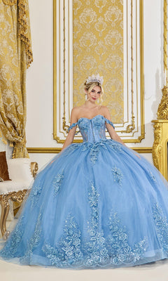 A woman stands in an opulent room adorned with gold decor and intricate curtains, wearing the Quinceanera Dress 5117 by Dancing Queen in Smoky Blue, featuring a glitter tulle ballgown skirt and an ornate corset bodice.