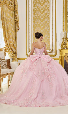 In an opulent room adorned with gold accents, a woman stands facing away from the camera, her hair elegantly styled in an updo. She wears the Quinceanera Dress 5119 By Dancing Queen—an exquisite pastel pink ball gown featuring a corset bodice, a dramatic bow, and intricate floral details that beautifully highlight her silhouette. The luxurious setting enhances the graceful charm of both the dress and its wearer.