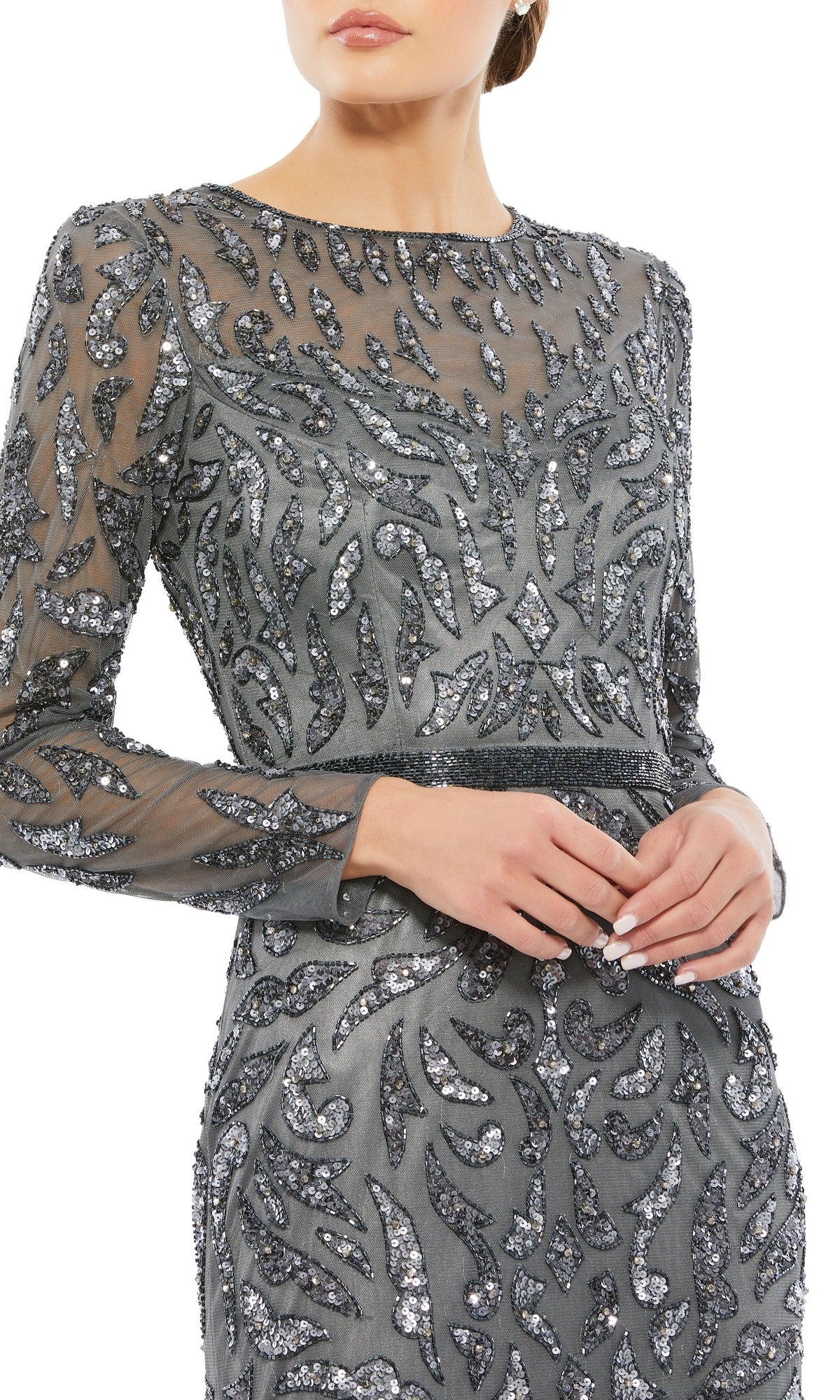 A woman in a silver-grey Mac Duggal 5124 Long Sleeve Sequin Formal Dress, featuring sheer fabric and intricate patterns, shown from shoulders to mid-thigh.