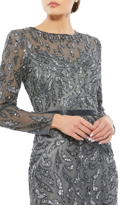 A woman in a silver-grey Mac Duggal 5124 Long Sleeve Sequin Formal Dress, featuring sheer fabric and intricate patterns, shown from shoulders to mid-thigh.