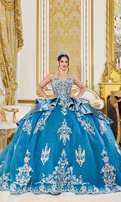 A young woman in the Dusty Teal Quinceanera Dress 5125 by Dancing Queen, featuring glitter tulle and beaded appliqué, stands in an elegant room with gold baroque-style décor, wearing a sparkling tiara.