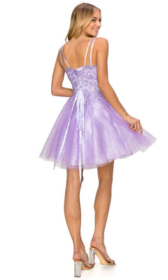 A woman in the Corset-Back Short Glitter Homecoming Dress 5125J, featuring double spaghetti straps and a lace-up back, stands in clear heels facing away and looks over her shoulder.