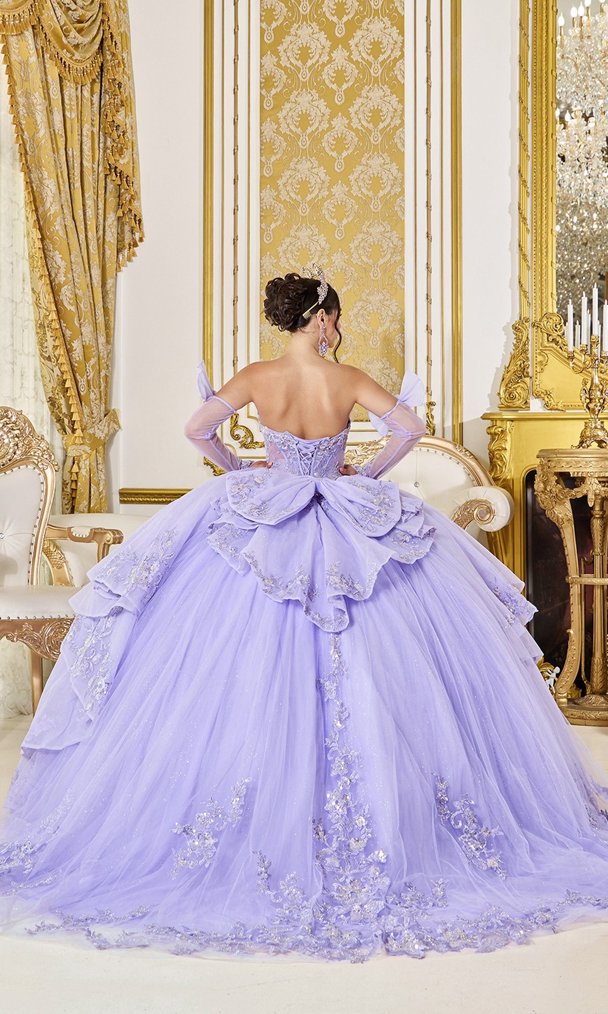A lavender lilac Quinceanera Dress 5129 By Dancing Queen featuring a beaded corset bodice, sheer sleeves, a full ruffled skirt, and silver floral embroidery.