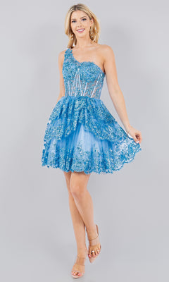 A woman wearing the One-Shoulder Short Tiered Homecoming Dress 5132J, featuring bright blue floral lace and sheer panels, stands against a plain light gray background.