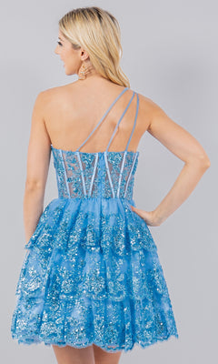 A woman with long blonde hair models the One-Shoulder Short Tiered Homecoming Dress 5132J in sparkly blue, featuring sheer panels and asymmetrical straps, standing with her back to the camera.