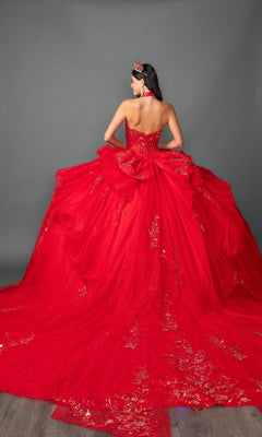 A woman faces away, wearing the Dancing Queen Quinceanera Dress 5159—a strapless red ballgown featuring a beaded corset bodice, layered ruffle skirt embellished with gold accents, and a matching red crown—standing against a plain gray background.