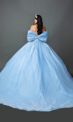 A woman stands facing away against a plain gray background, wearing the Quinceanera Dress 5160 By Dancing Queen—a light-blue ballgown featuring a corset bodice and a large bow on the back—paired with a tiara.
