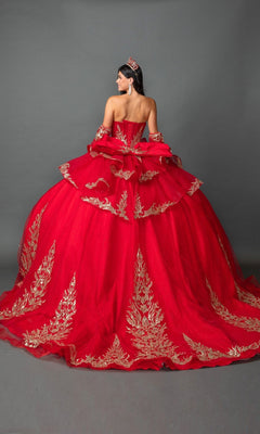 A woman stands against a gray backdrop, facing away from the camera, wearing the Quinceanera Dress 5161 By Dancing Queen—a strapless ballgown in vibrant red adorned with gold embroidered appliques. She accessorizes with matching gloves and a red tiara, highlighting the exquisite detailing and timeless elegance of this stunning gown.