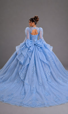 Back view of a light-blue Quinceanera Dress 5167 By Dancing Queen, featuring long sheer sleeves, a lace-up corset, and a voluminous, layered skirt with embroidered lace appliques and a large back bow.