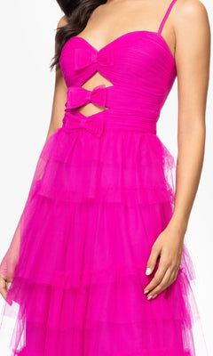 A woman wears the Long Hot Pink Prom Dress: Blondie Nites 5187BN, featuring spaghetti straps, a ruched sweetheart bodice, tiered tulle skirt, and two bow cutouts—an eye-catching prom dress under $200.