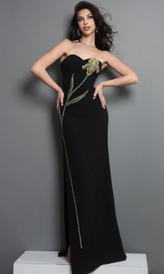 A woman wears the Long Formal Dress: Jovani 51902, a striking black strapless gown featuring intricate green and gold beaded floral embellishments, as she stands against a gray background.