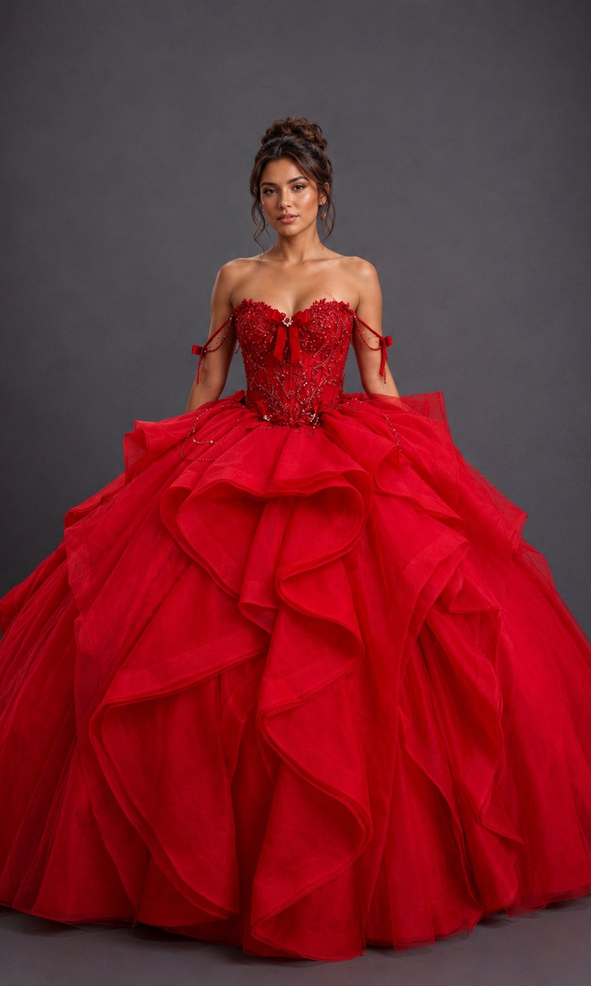 A woman poses against a plain dark background wearing the Quinceanera Dress 5197 by Dancing Queen in red, featuring a dramatic off-the-shoulder design with a beaded corset bodice and a layered tulle ball gown skirt.