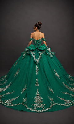 A woman stands facing away against a dark background, wearing the Quinceanera Dress 5198 By Dancing Queen—an off-the-shoulder green ball gown adorned with silver embroidery and featuring a fitted corset bodice.