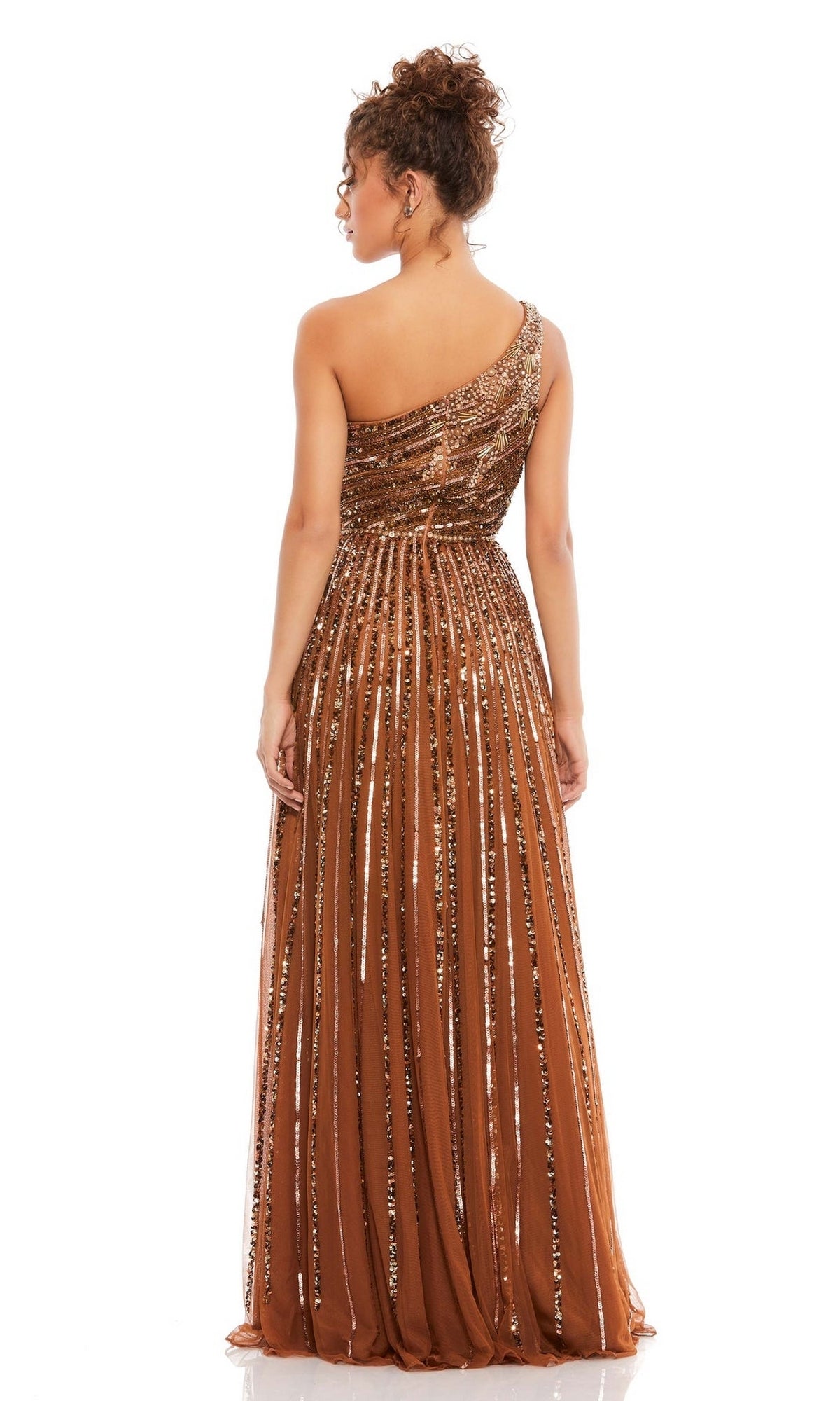 A woman stands with her back to the camera in the Mac Duggal 5220, a brown one-shoulder beaded formal dress with sequin detailing, set against a white background.