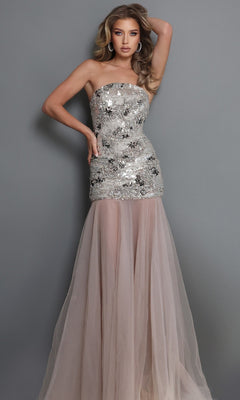 A woman wearing the Jovani 52538 long formal dress in taupe and silver, featuring a strapless fitted bodice embellished with shimmering silver sequins and delicate crystal beadwork, and a sheer, flowing taupe tulle skirt, stands against a plain gray background.