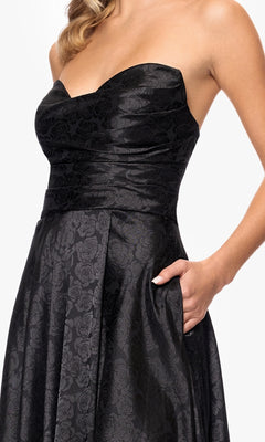 A woman in the Blondie Nites 5301BN strapless black prom gown with a floral pattern and skirt pocket, ideal for junior sizes and an elegant evening look.