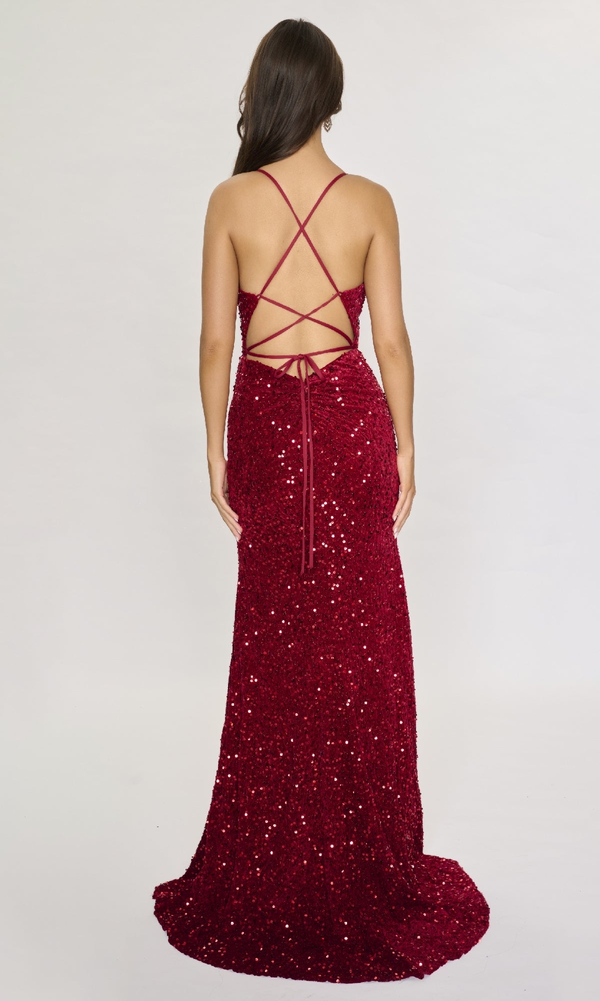 A woman models the Nina Canacci 5302, a floor-length formal dress featuring sequins, a high-leg slit, and a strappy open back, against a plain light background.