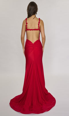 A woman models the Nina Canacci 5304, a floor-length formal dress featuring a backless design and 3D rose accents on the straps, against a plain light background.
