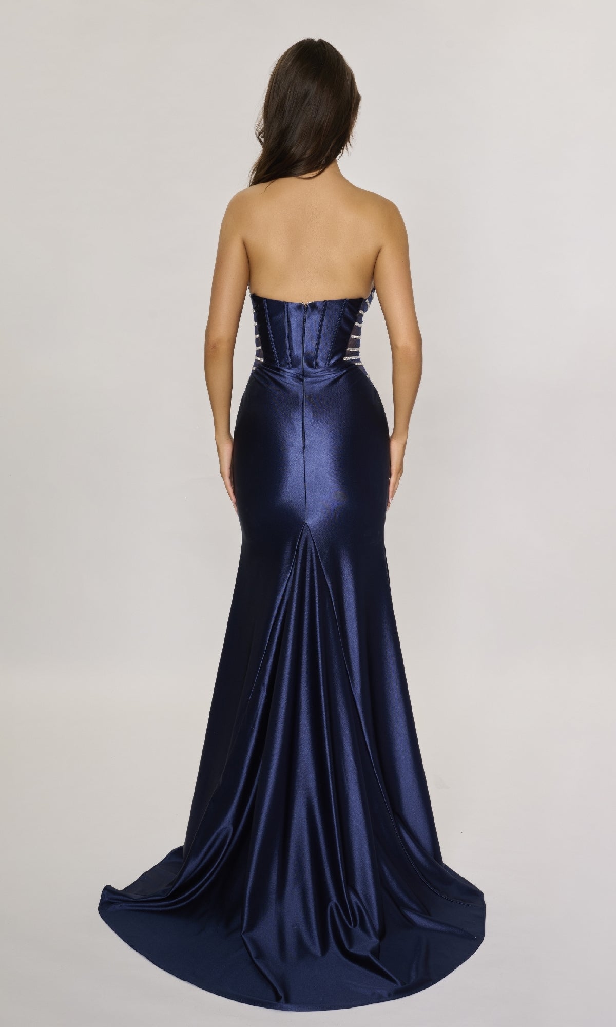 A woman is shown from the back wearing the Nina Canacci 5307 long formal dress—a strapless, fitted satin gown in navy that flows floor-length against a plain light background.