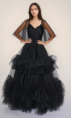 A woman stands with hands on hips, wearing the Nina Canacci 5315 long formal dress with ruffle tiered tulle and sheer sleeves, set against a plain light background.