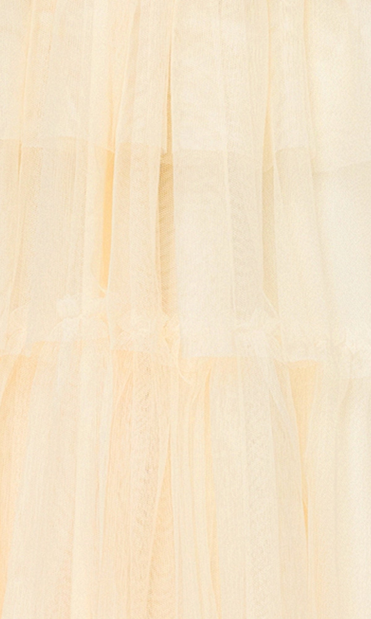 Close-up of soft, layered, cream-colored tulle with a semi-transparent look, similar to the delicate texture featured on the Long Yellow Halter Prom Gown: Blondie Nites 5349BN.