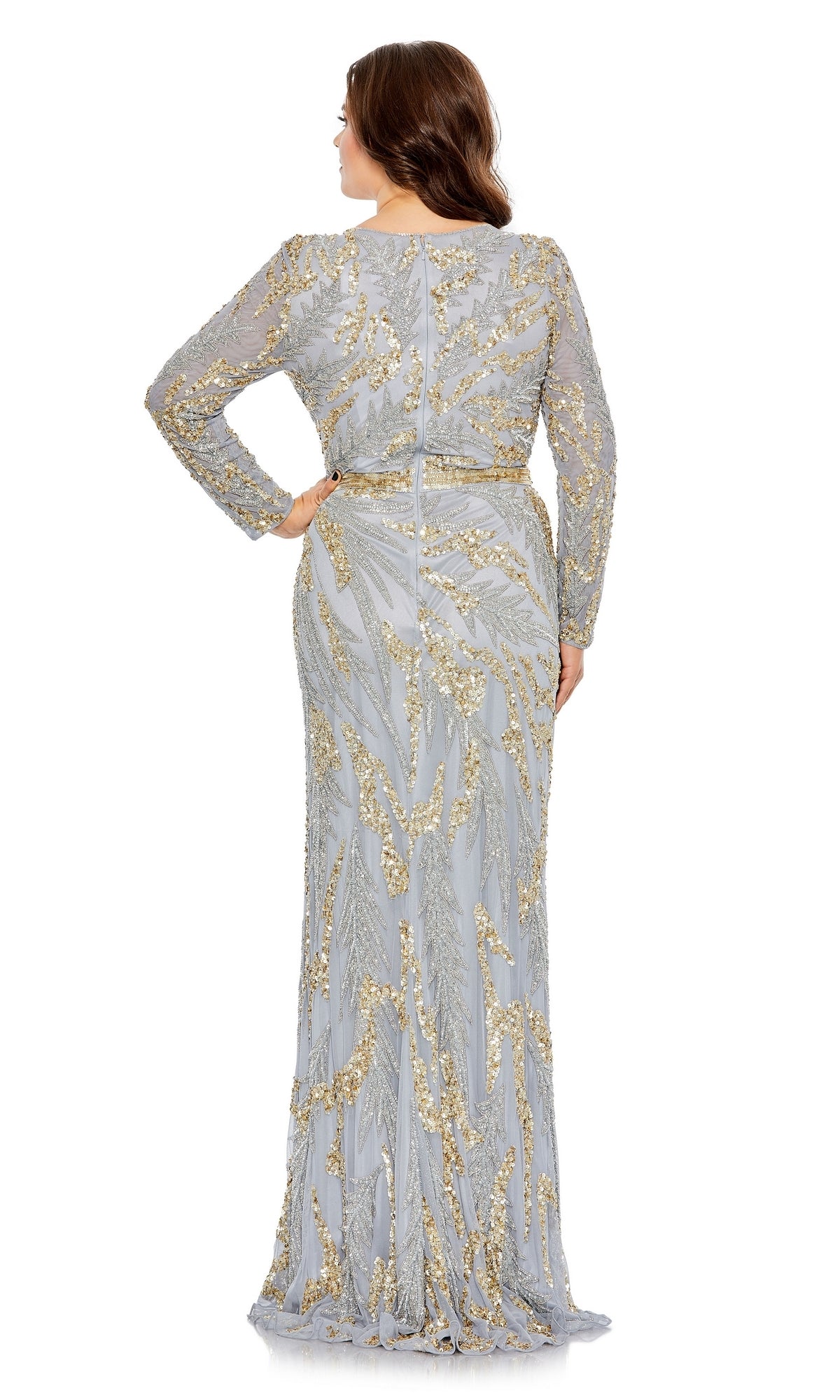 A woman stands with her back to the camera wearing the Long Plus-Size Formal Dress 5358 by Mac Duggal, a floor-length silver and gold gown featuring long sleeves and intricate gold embroidery.