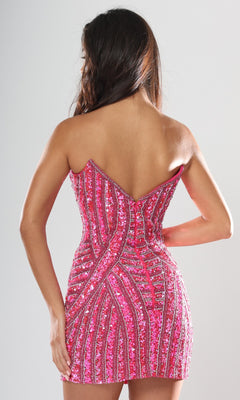 A woman faces away, modeling the Jovani 53769 Short Homecoming Dress—a strapless, fitted, short pink sequin dress featuring geometric beading and a V-shaped back—against a plain light background.