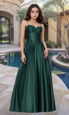 A woman stands on a stone patio by a pool, wearing the Blondie Nites 5387BN Classic Long Prom Dress in Hunter, featuring an embroidered-lace corset, with landscaped plants and a building in the background.