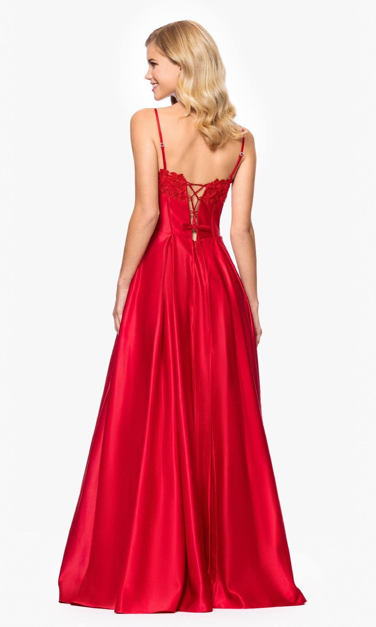 A woman stands facing away, wearing the Classic Long Prom Dress: Blondie Nites 5387BN in bold red satin, featuring a stunning lace-up back and reminiscent of a sweetheart prom style.