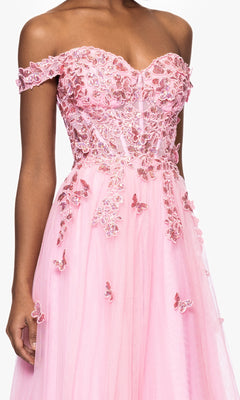 A person wearing the Blondie Nites 5389BN blush pink prom dress, which features a sweetheart corset bodice, floral and butterfly appliqué accents, and delicate beaded floral lace embroidery on the skirt.
