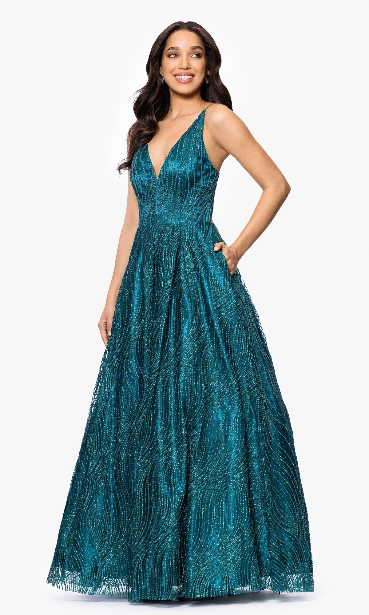 A woman poses against a white background in the Blondie Nites 5406BN Long Glitter Prom Dress, a teal, floor-length gown featuring a deep V-neckline, textured patterns, and pockets.