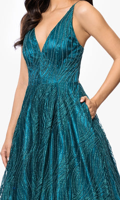 Woman wearing the Long Glitter Prom Dress: Blondie Nites 5406BN, a sleeveless teal gown with a deep V-neckline and shimmering textured patterns, posing with one hand on her waist.