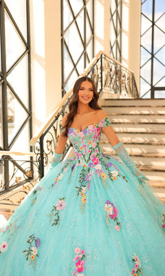 A woman wearing the Quinceanera Dress 54200 by Amarra, an off-the-shoulder gown with floral embroidery, stands at the base of a staircase in a sunlit, elegant interior.