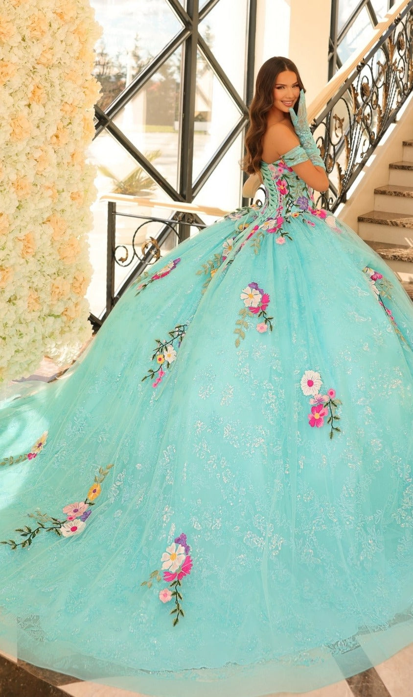 A woman wearing the Quinceanera Dress 54200 By Amarra, featuring off-the-shoulder floral embroidery, stands on a staircase looking over her shoulder and smiling.