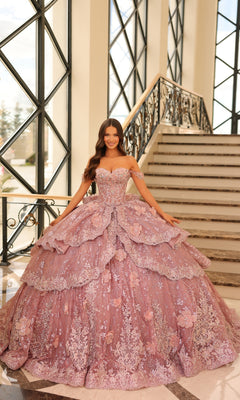 A woman in the Quinceanera Dress 54202 By Amarra, a detailed off-the-shoulder lavender ball gown, stands at the base of an ornate staircase with large windows behind her.