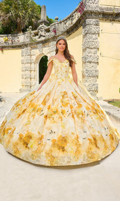 A young woman stands outdoors before a stone archway, wearing the Quinceanera Dress 54208 by Amarra, a floor-length ball gown with a yellow and white floral print.