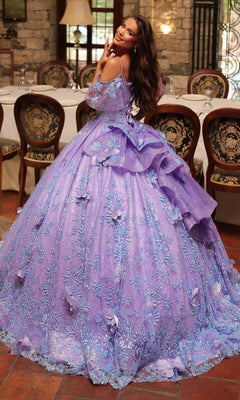 A woman smiles in a formal dining room with ornate chairs and stone walls, wearing the Amarra 54229 glitter tulle quinceañera dress featuring lavender hues, floral details, and delicate beading.