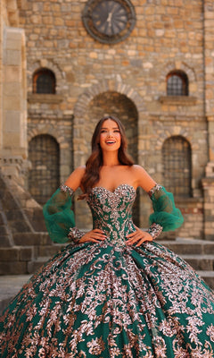 A woman wearing the Amarra 54238 Sequin Quinceanera Dress with puff sleeves smiles in front of a stone building featuring arched windows and a large clock.