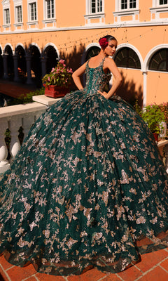 A woman in the Amarra 54260 Corset Quincea¤era Dress with Cloak stands on a terrace, facing away, with a large building and arches in the background.