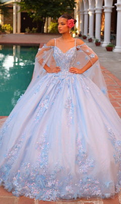 A woman wearing the Quinceanera Dress 54306 By Amarra, featuring a light blue ball gown with a corset bodice and floral embroidery, stands by a pool with flowers in her hair and an ornate building behind her.