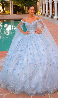 A woman stands by a pool wearing the Quinceanera Dress 54308 by Amarra, a light blue off-shoulder ball gown with sparkles, 3D floral details, and sheer cape sleeves.