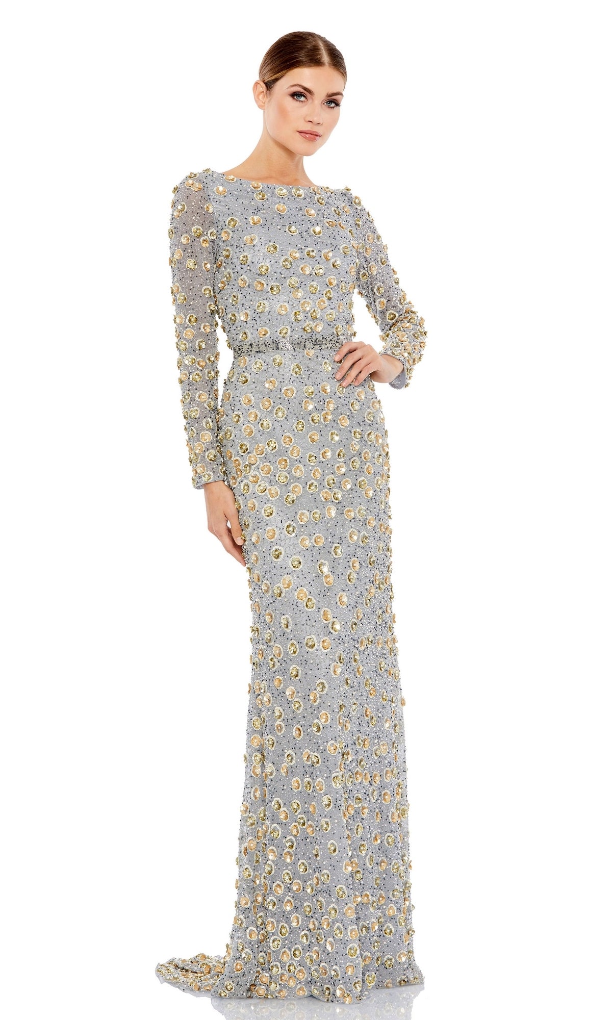 A woman stands against a white background wearing the Long Formal Dress 5437 by Mac Duggal, a floor-length silver gown with gold floral embellishments and long sleeves.